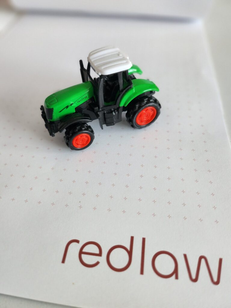 green toy tractor on redlaw notebook
